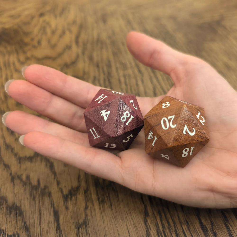 Oversized 33mm wooden D20 dice held in a hand to show its scale.