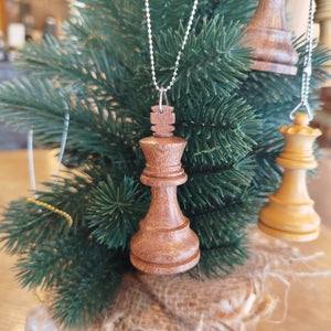Wooden chess piece ornaments hanging on a Christmas tree.