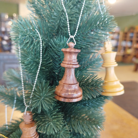 Decorative Christmas tree with wooden chess piece ornaments in a room setting.