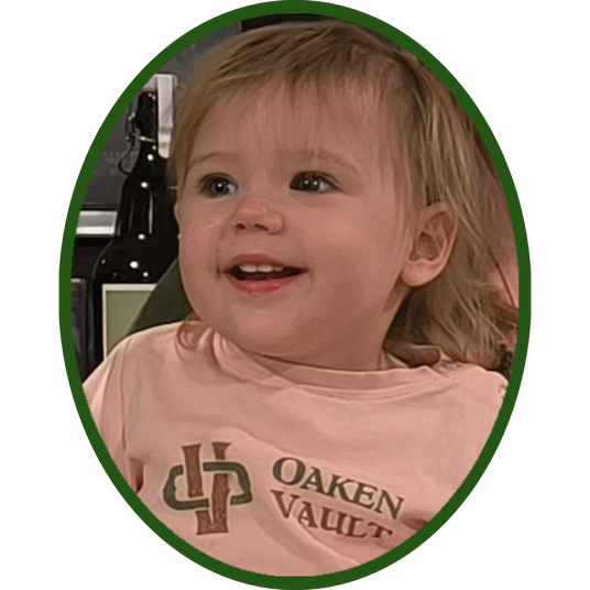 A photo of Nora, looking overjoyed after the tour. She has a wide, open-mouthed smile and is wearing a pink shirt with the words 'Oaken Vault' and our company logo.
